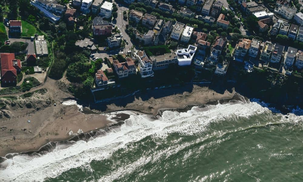 Aerial view of coastal homes near the shoreline, showing why a boundary line survey is important in shoreland zones