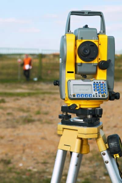 Surveying equipment set up on a property line to conduct a boundary line survey after storm damage
