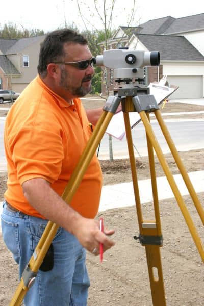 Land surveyor restoring boundary lines - ALTA SURVEY Maine Land surveyor using a level and tripod to re-establish property boundaries after coastal erosion.