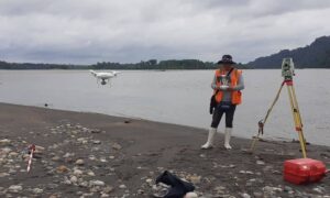 Land surveyor conducting an ALTA survey with drone and total station near a coastal site