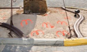 Spray paint layout marks on sandy ground showing where a construction staking survey guides a coastal rebuild before pouring concrete