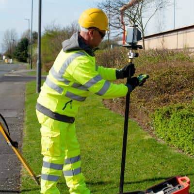 Licensed land surveyor collecting on-site elevation data for a certified topographic survey using GNSS equipment