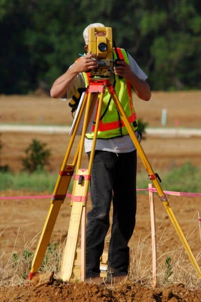 Land surveyor measuring property - ALTA SURVEY Maine Topographic survey in progress with a surveyor measuring land elevation on a property