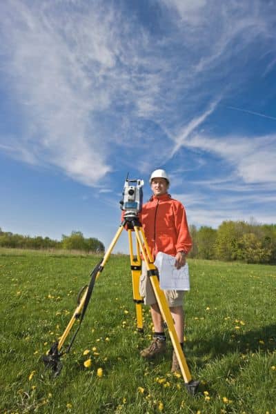 Land surveyor performing a boundary survey using a total station to measure property lines